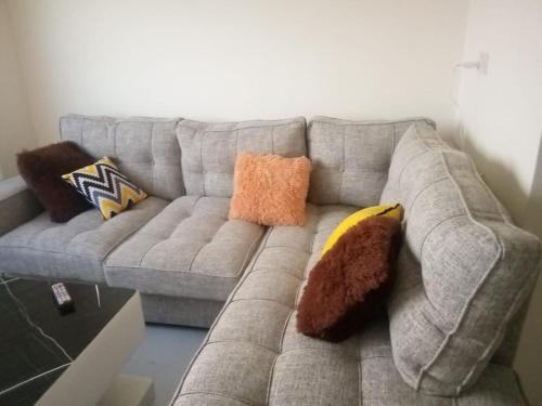 um sofá com almofadas na sala de estar em Rozina Apartments em Nairobi