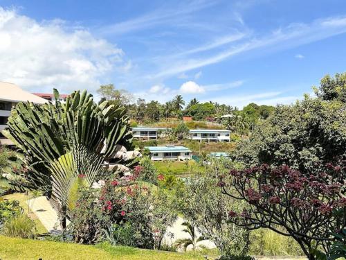 a garden with flowers and trees and buildings at FARE Moea - TAHITI in Arue
