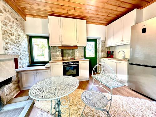 a kitchen with white cabinets and a table and chairs at Waterfall Kataraktis Vatatsi in Vatátsion
