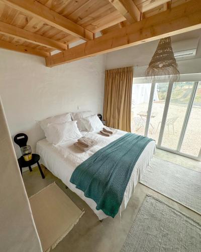 a bedroom with a bed and a large window at Valle D`Água - Casas de campo in Vale de Água
