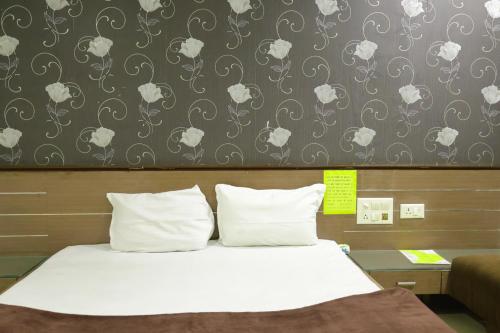 a bed with white pillows in a room at Hotel Neelkanth , Bhopal in Bhopal