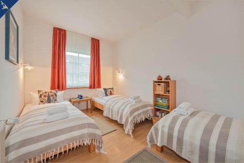 1 dormitorio con 2 camas y una ventana con cortinas rojas en Lütow Ferienhaus an der Südspitze Gnitz, en Lütow