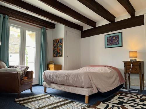 a bedroom with a bed and a chair and a window at Les Amis du Moulin 