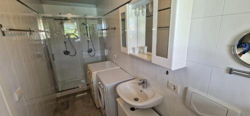 uma casa de banho branca com um lavatório e um chuveiro em Casa Romantica em Colico