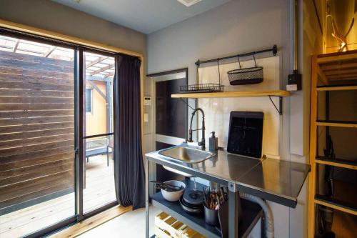 a kitchen with a sink and a large window at 日向サーフキャンプ110 in Hyuga