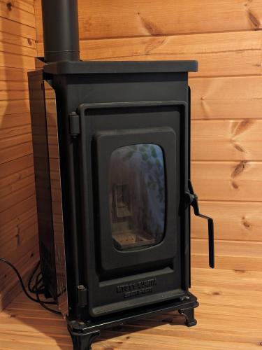 a black stove sitting on top of a wooden floor at Eco-friendly Log Cottage - be with nature in Furano