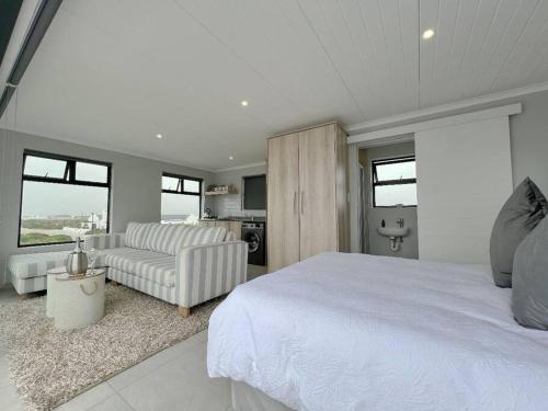 ein Schlafzimmer mit einem weißen Bett und ein Wohnzimmer in der Unterkunft Seeswael Strand in Velddrif