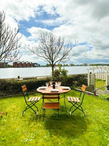 a table and four chairs in a yard with a lake at Ferienwohnung Havenblick in Wilhelmshaven