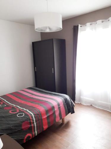 une chambre avec un lit avec une couverture rayée dans l'établissement Chambre Salon Sdb Jardin près Bordeaux, à Cestas