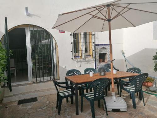 una mesa y sillas con una sombrilla en el patio en Casa adosada Marina playa y golf, en San Luis de Sabinillas