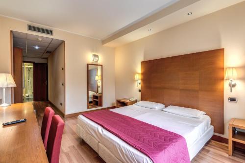 オレッジョ・カステッロにあるLuna Hotel Motel Lago Maggiore Aronaの大きなベッドとデスクが備わるホテルルームです。