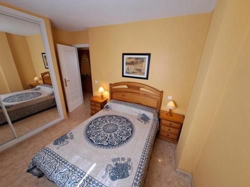 a small bedroom with a bed and a mirror at Apartamentos Marinesco V.v. in La Manga del Mar Menor