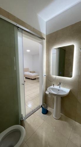 a bathroom with a sink and a toilet and a mirror at Hotel Skura in Librazhd