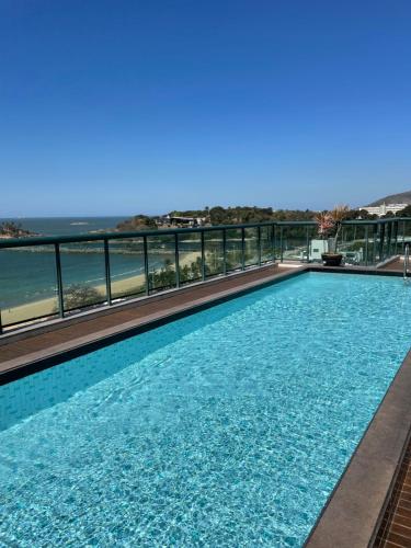 a swimming pool with a view of the ocean at Flat Praia Century Camburi in Vitória