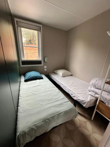 - 2 lits dans une petite chambre avec fenêtre dans l'établissement Mobile-home tout équipé avec Jacuzzi, à Porto-Vecchio