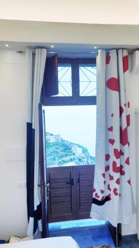 a bedroom with a window and a door with a view at Amalfi Rooms Duoglio Beach -amazing seaview in Amalfi