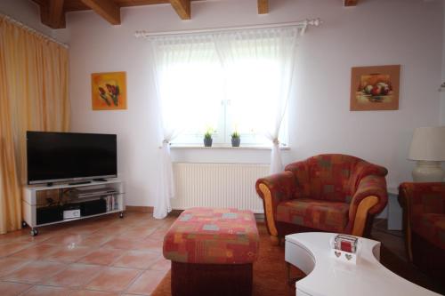 Una sala de estar con un televisor, un sofá y una silla. en Hermer Bungalow, en Grömitz