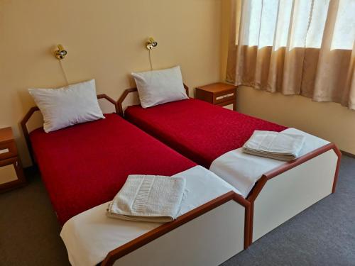 twee bedden in een kamer met rood en wit bij Доли in Pomorie
