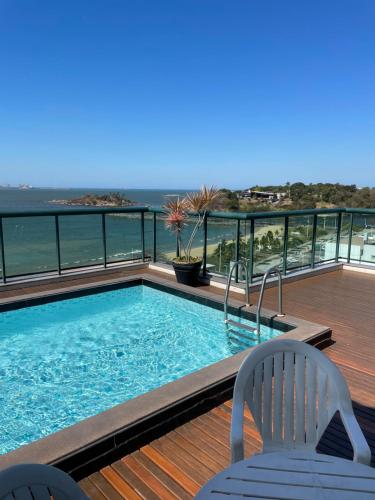 a swimming pool on a deck with a view of the ocean at Flat Praia Century Camburi in Vitória