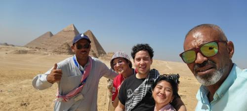 um grupo de pessoas em pé na frente das pirâmides em Pyramids Temple Guest House no Cairo