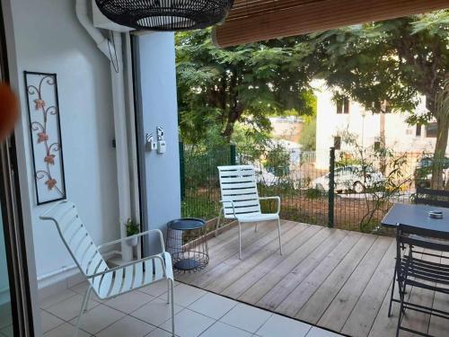 a porch with two chairs and a table and a fence at Les aigrettes in Saint-Paul