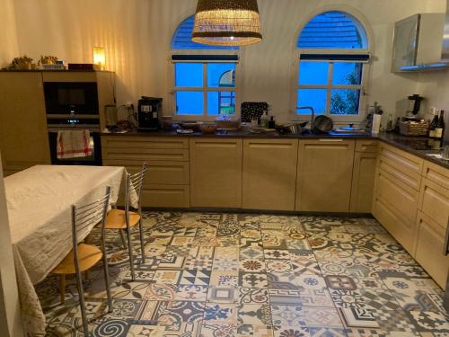eine Küche mit einem Tisch und einigen Fenstern und einem Boden in der Unterkunft Maison située à Montmorency (95) disponible pour les JO in Montmorency