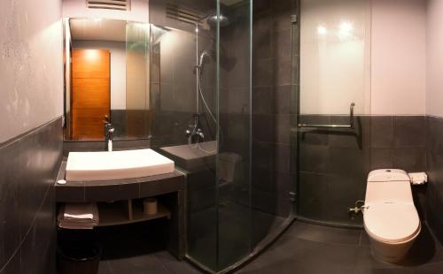 a bathroom with a shower and a toilet and a sink at Transera Kamini Legian Hotel in Legian