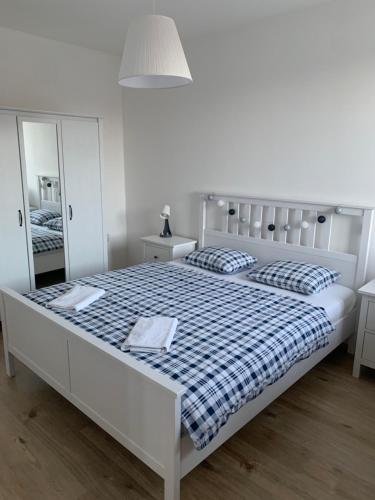 a white bedroom with a large white bed with a blue and white blanket at Apík Hartmanice in Hartmanice
