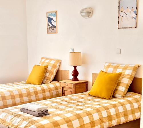 2 camas con almohadas amarillas en una habitación en Maison Notre Dame des Apôtres en Capbreton