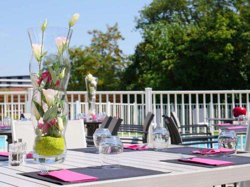 stół z wazonem kwiatów w obiekcie Mercure Annemasse Porte De Genève w mieście Gaillard