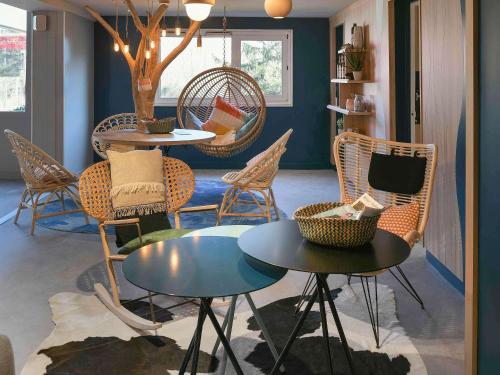 ガイヤールにあるメルキュール アンヌマス ポルト ドゥ ジュネーブのテーブル2台、椅子、テーブルと椅子が備わる客室です。