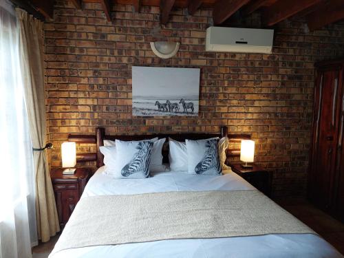 a bedroom with a bed and a brick wall at Khumbula iAfrica 1 in Marloth Park
