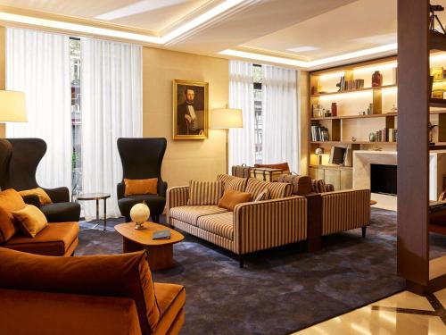 a living room with couches and a fireplace at Sofitel Paris Baltimore Tour Eiffel in Paris