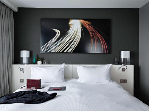 a bedroom with a white bed with a painting on the wall at Pullman Paris La Défense in Courbevoie