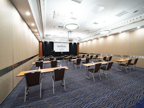 a conference room with tables and chairs and a projection screen at Novotel Sydney Brighton Beach in Sydney