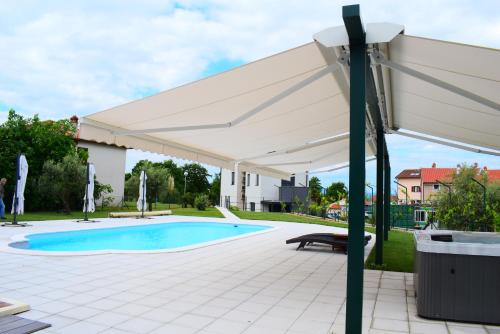 a white patio umbrella over a swimming pool at Apartment Nika in Njivice
