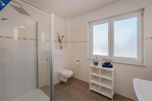 een badkamer met een douche, een toilet en een raam bij Villen am See - Villa Petra Whg Ahlbeck in Korswandt