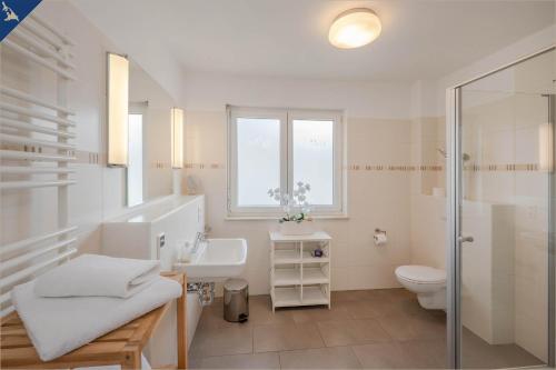 a white bathroom with a sink and a toilet at Villen am See - Villa Petra Whg Bansin in Korswandt