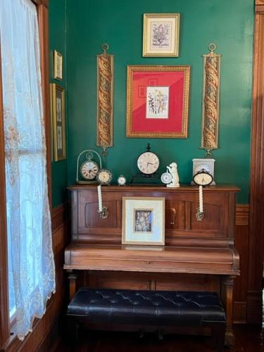 a green room with a wooden table with clocks on the wall at Woodbine Inn and Restaurant in Madisonville