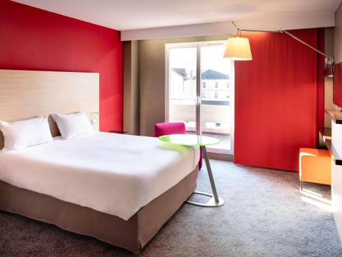 サン・ディジエにあるibis Styles Saint Dizierの大きなベッドとテーブルが備わるホテルルームです。