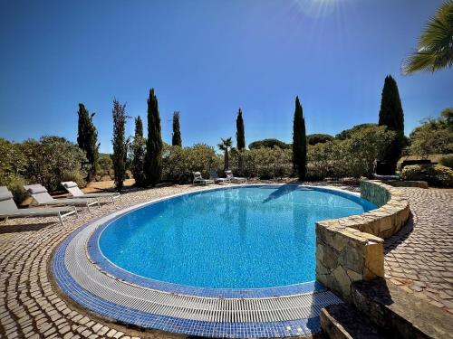 a swimming pool in a yard with chairs and trees at Quarteira Premium Villa With Pool by Homing in Quarteira