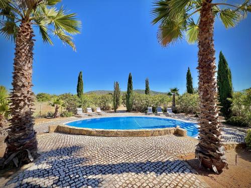 a swimming pool with two palm trees and chairs at Quarteira Premium Villa With Pool by Homing in Quarteira