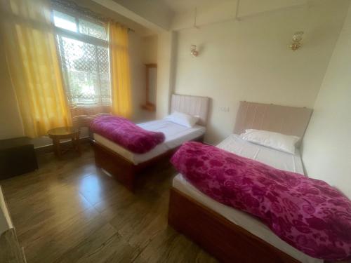 a room with two beds with purple blankets on them at Namo Sai Homestay in Darjeeling