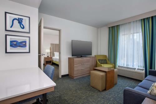 a hotel room with a television and a room with a bed at Homewood Suites by Hilton Davidson in Davidson