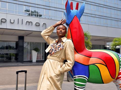 a woman standing next to a statue of a colorful donkey at Pullman Kinshasa Grand Hotel in Kinshasa