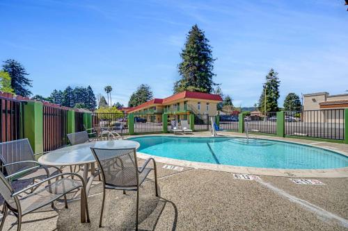 a pool with a table and chairs next to a fence at Quality Inn Santa Cruz Downtown Area in Santa Cruz