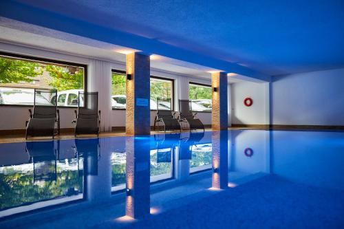 a room with a swimming pool with chairs in it at Flair Hotel Sonnenhof in Baiersbronn