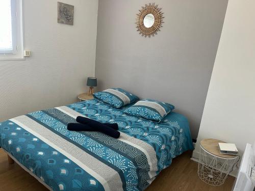 une chambre avec un lit avec des draps bleus et un miroir dans l'établissement Appartement meublé en plein coeur de ST VALERY EN CAUX, à Saint-Valery-en-Caux