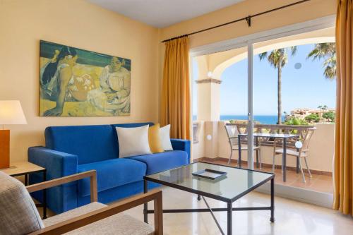 a living room with a blue couch and a table at Wyndham Grand Costa del Sol in Mijas Costa