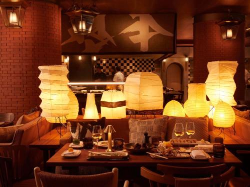 a restaurant with a table with plates of food and lamps at Mondrian Bordeaux Les Carmes in Bordeaux